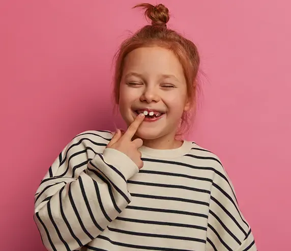 Menina sorridente mostrando o dente de leite