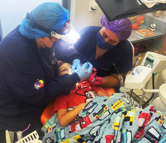 Equipe atendendo uma criança na cadeira odontológica