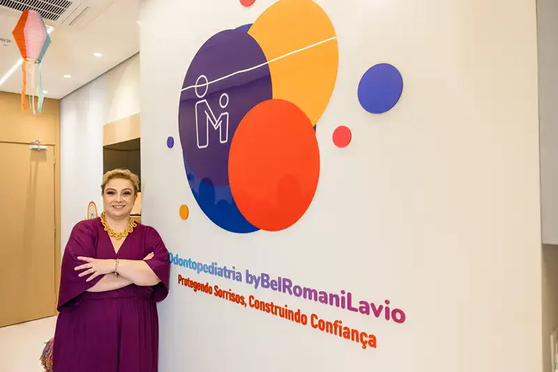 Dra. Bel Romani Lavio, odontopediatra em Campinas, em frente ao logotipo da clínica
